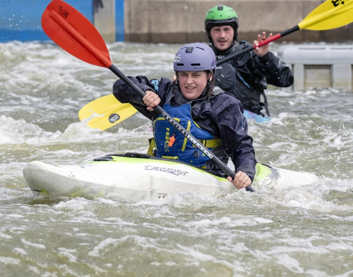 Two people kayaking in whitewater rapids, wearing helmets and waterproof gear during an outdoor activity session. Two people kayaking in whitewater rapids, wearing helmets and waterproof gear during an outdoor activity session.